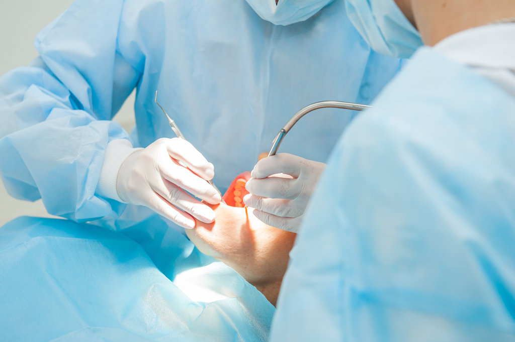 Close up dental surgery process - Implantation. Dentist surgeon with assistant in modern clinic. Stomatology and health care concept. selective focus. Space for text.