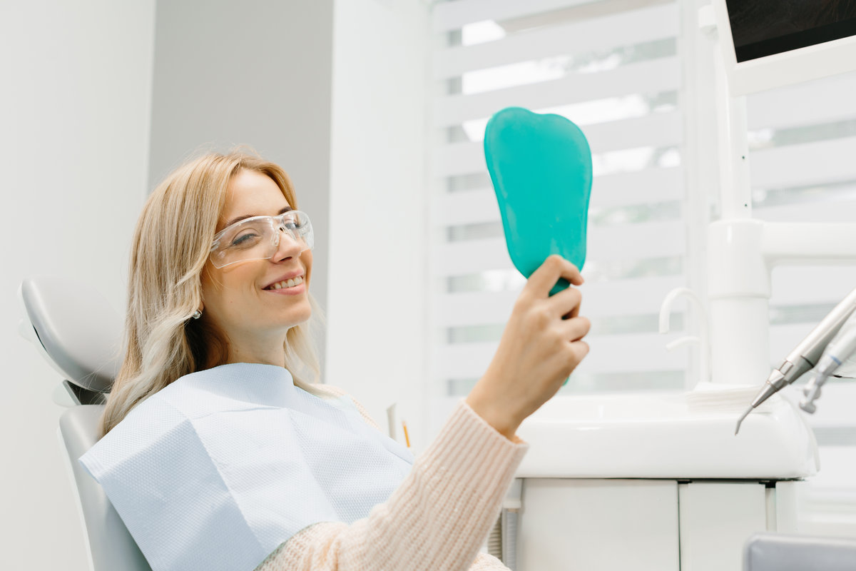 Woman looking at her teeth. Smiling lady at dentist office.