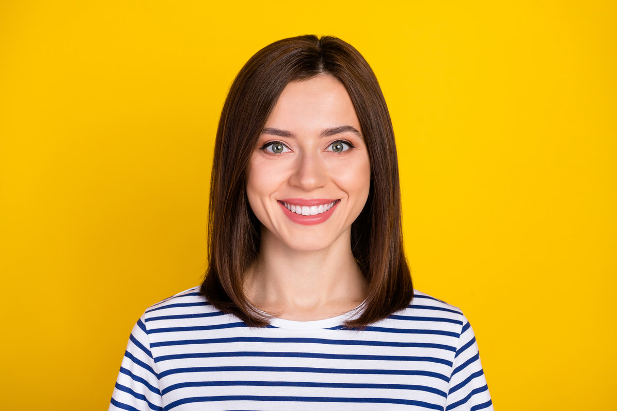Photo of nice cute pretty woman bob hairstyle dressed striped t-shirt toothy smiling dental advert isolated on yellow color background.