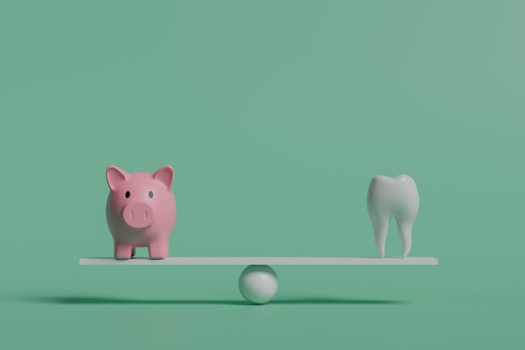 Piggy bank and tooth balancing on seesaw, concept of dental costs