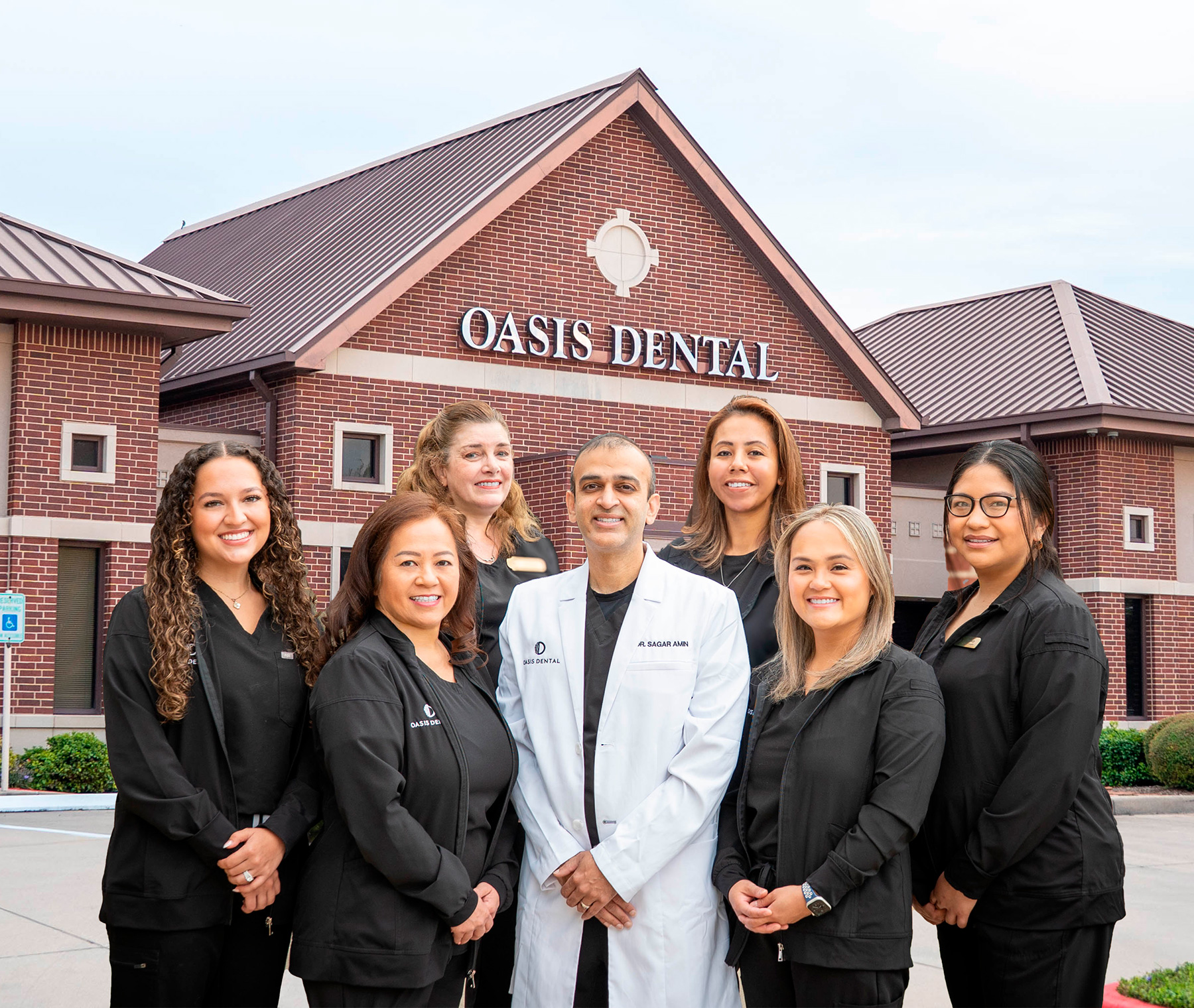 Dr. Sagar Amin and the professional dental team of Oasis Dental posing in front of the clinic building
