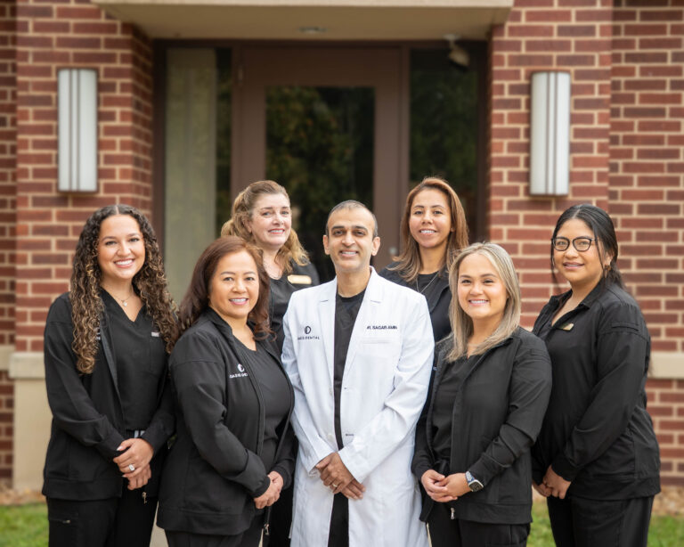Oasis Dental team of dentists and staff standing together in front of the clinic building.